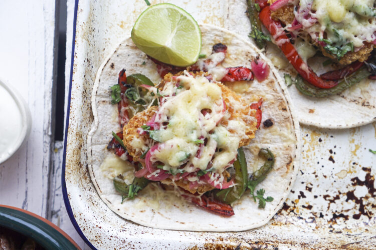 Delicious gluten free fried fish tacos with Mexican pickled red onions, spicy peppers with tajin seasonings, fresh coriander, cheese, sour cream and freshly squeezed lime juice