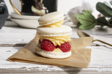 Homemade French macarons filled with custard flavoured buttercream and raspberries / Gluten free French dessert