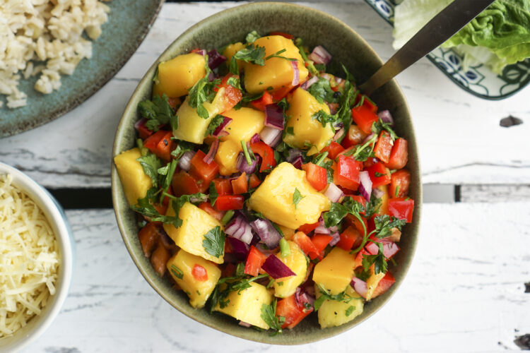 Delicious, healthy colourful mango salad with bell peppers, red onion, parsley, chilli and lime