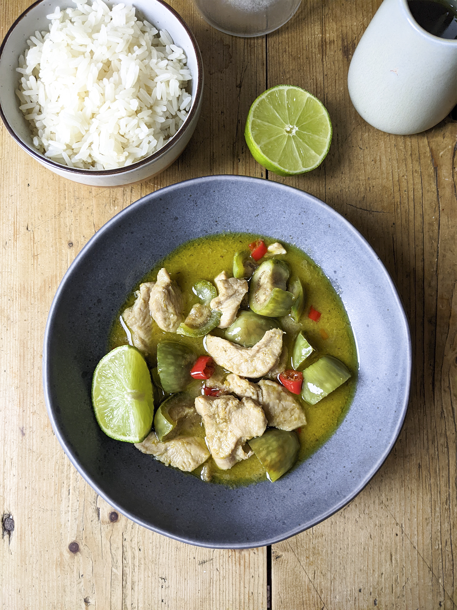 A basic authentic green Thai curry with chicken, Thai eggplants, lime and red chilli + a small bowl of rice on the side. Served in Tiger ceramic blue bowl.