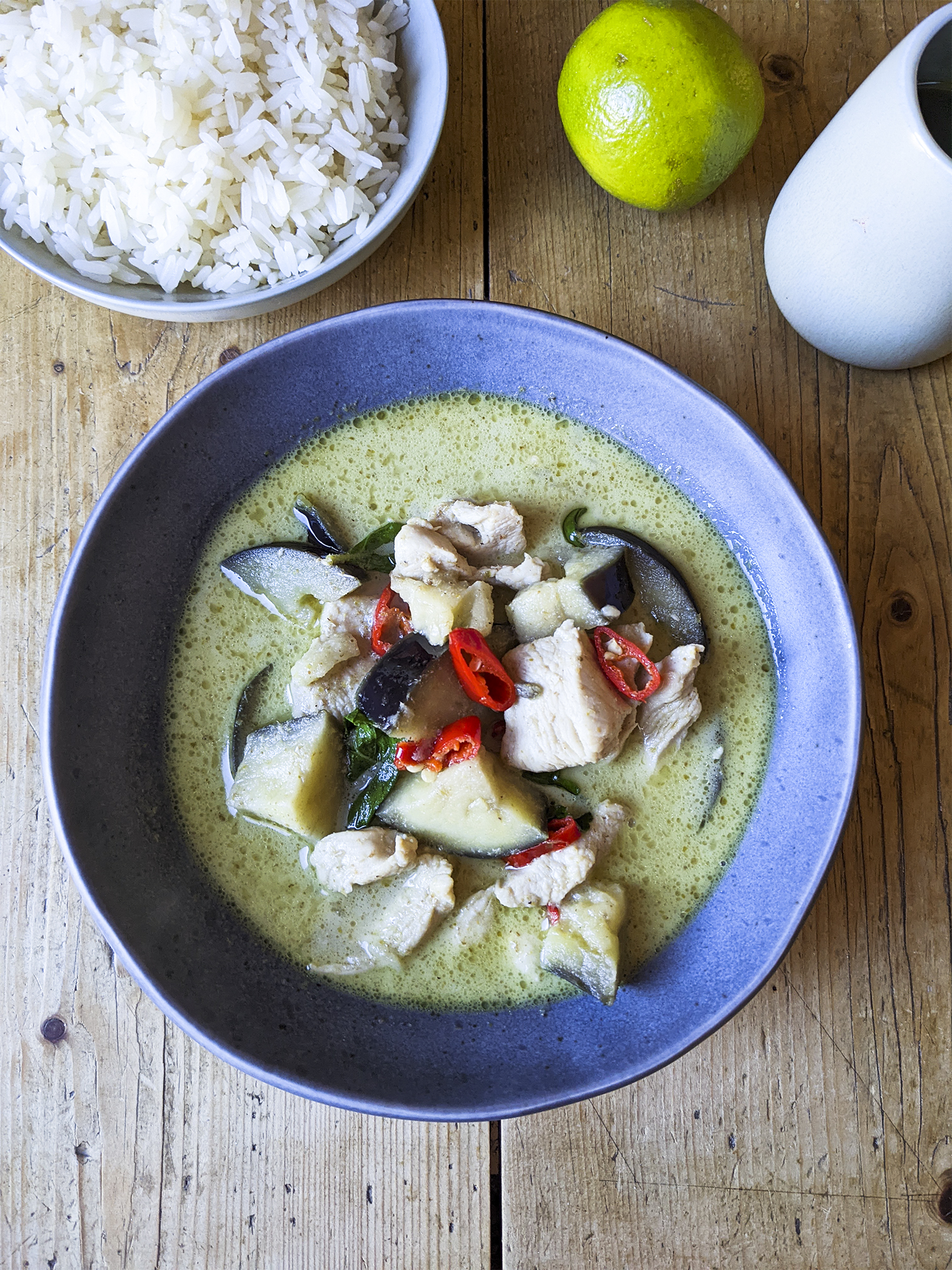 A basic authentic green Thai curry with chicken, aubergine, lime, Thai basil and red chilli + a small bowl of rice on the side. Served in Tiger ceramic blue bowl.